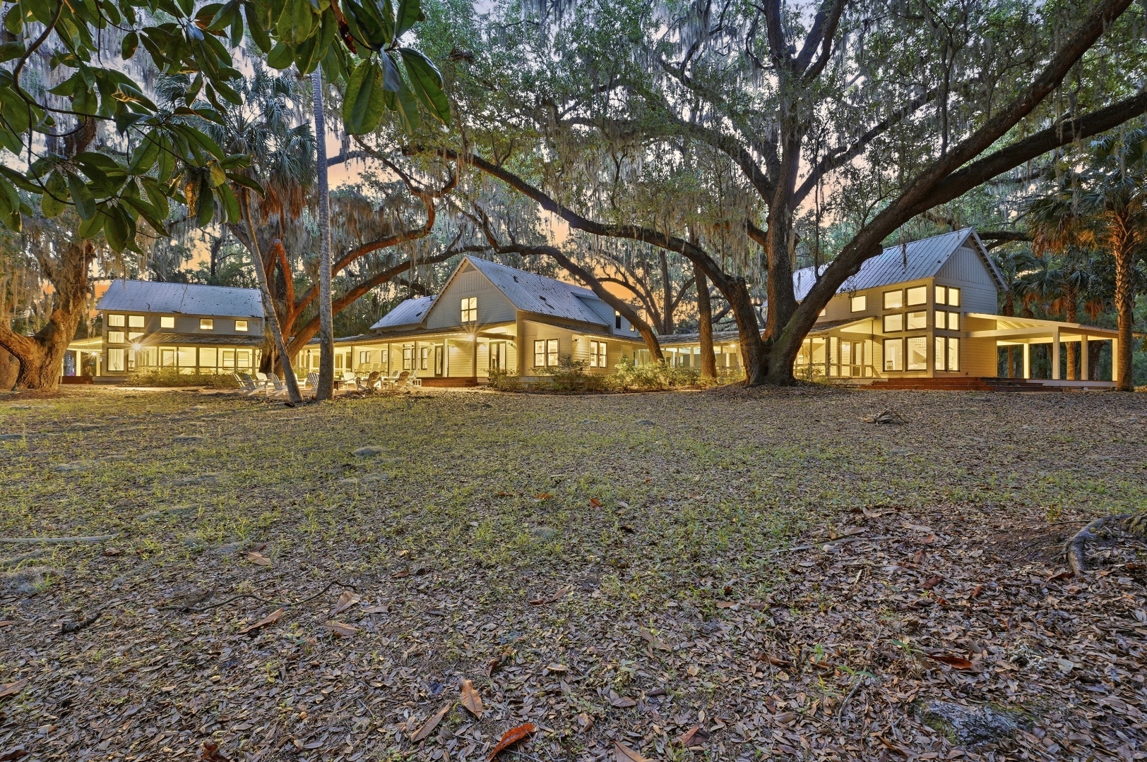 The estate compound at dusk under ancient live oaks